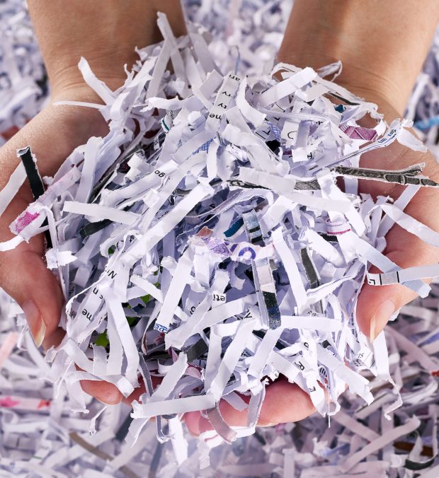 Studio shot of a womans hands holding a pile of shredded paper.